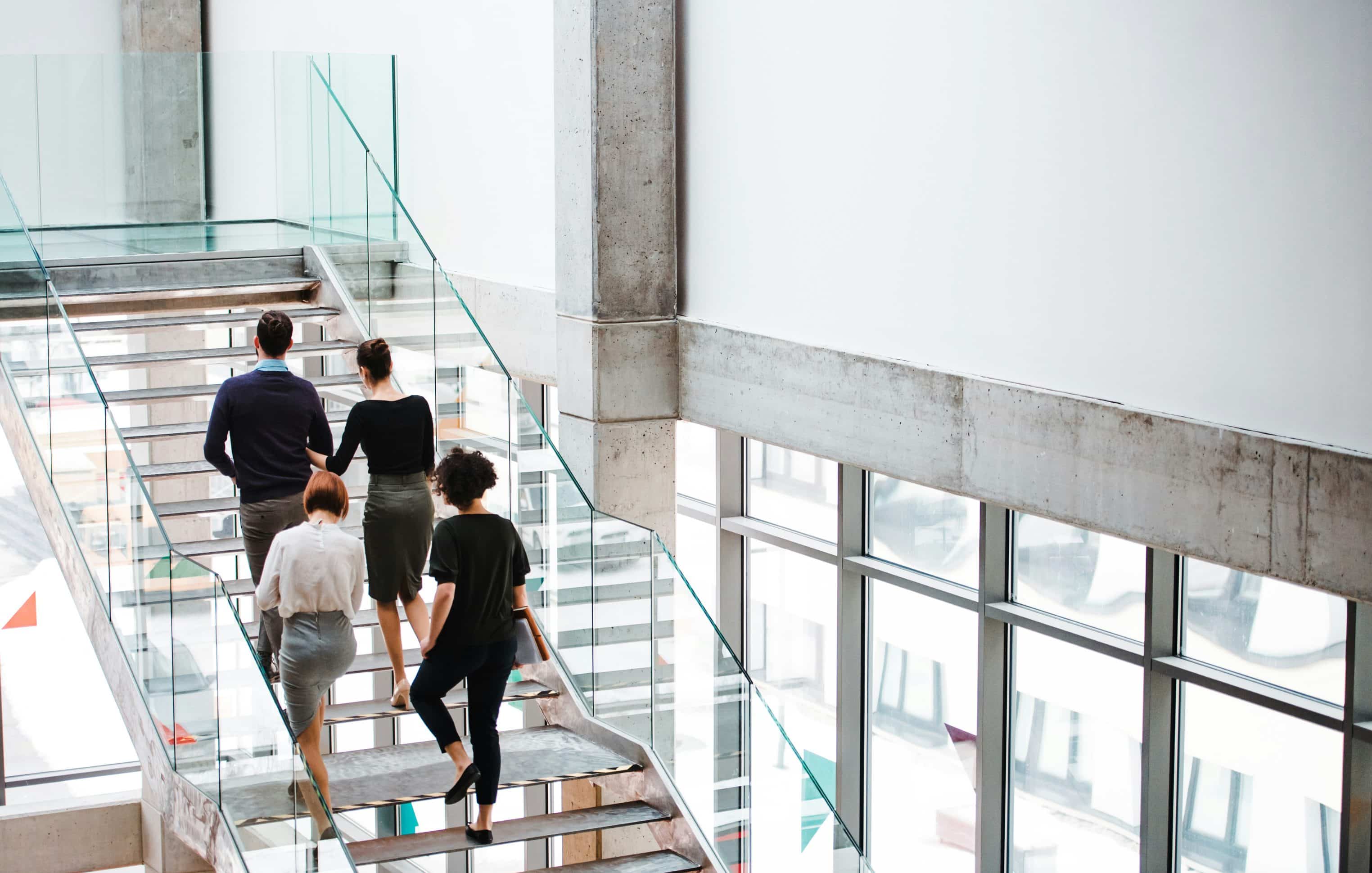 people walking up glass stairs